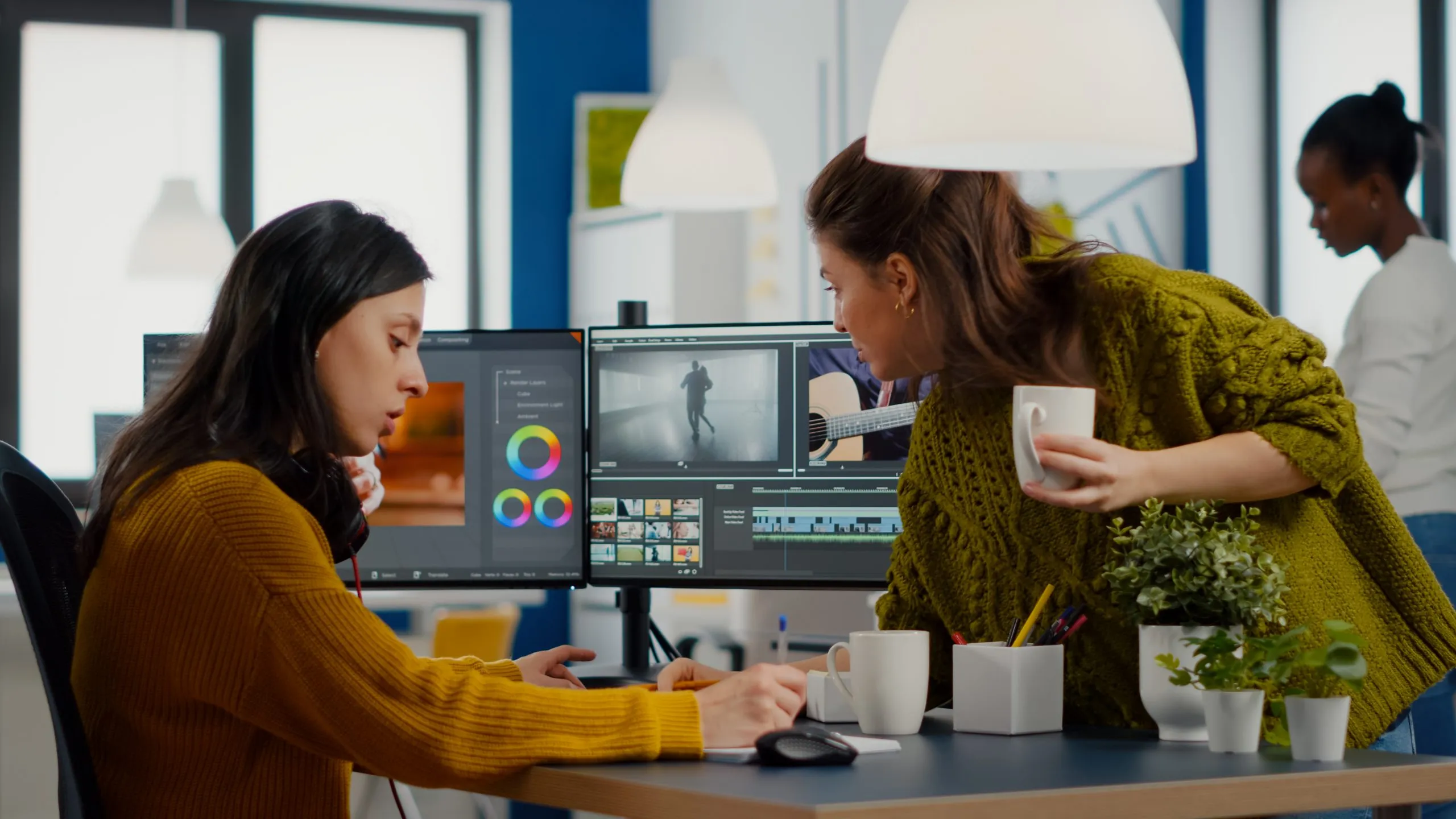 Colleagues discussing about video project adjusting film footage working in creative start up agency office with two monitors. Videographers processing movie montage with post production software