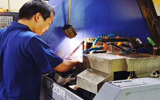 A CNC machine operator removing the finished product and inspecting its quality.